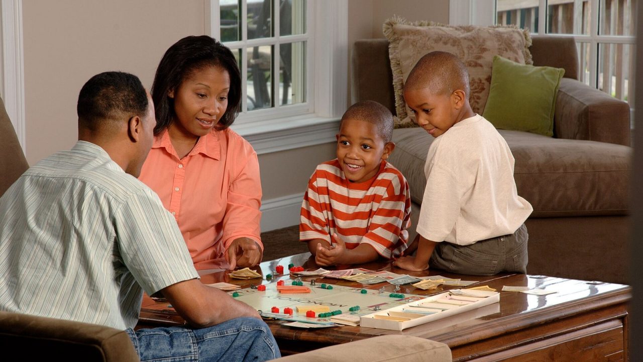 Family gathered around a coffee table playing a board game