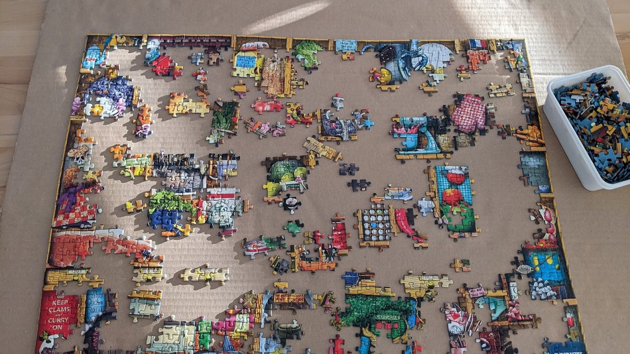 Partly completed jigsaw puzzle next to its box of loose pieces